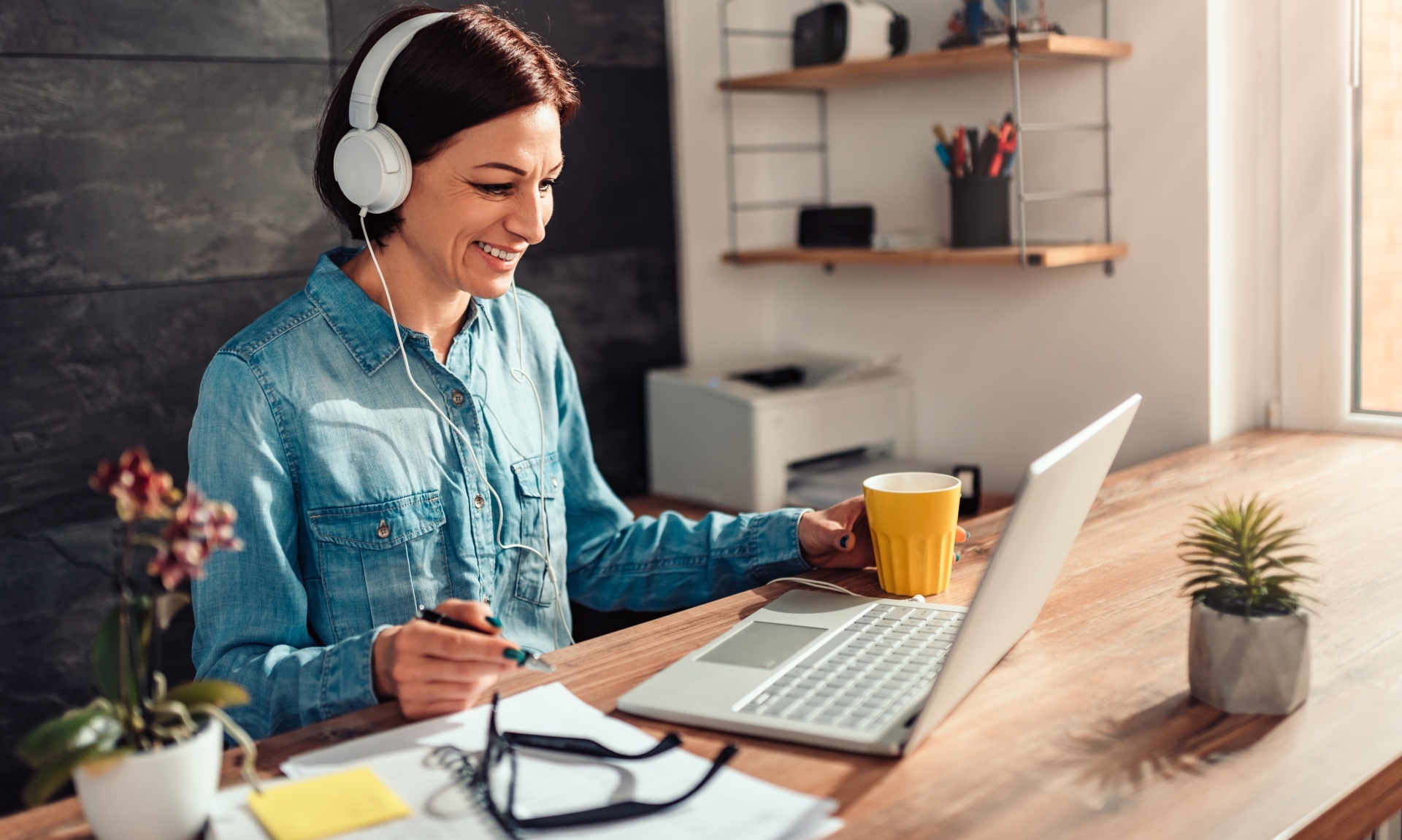 Business woman wearing white headphones doing video call at work